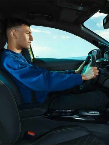 Een man bestuurt de PEUGEOT E-208