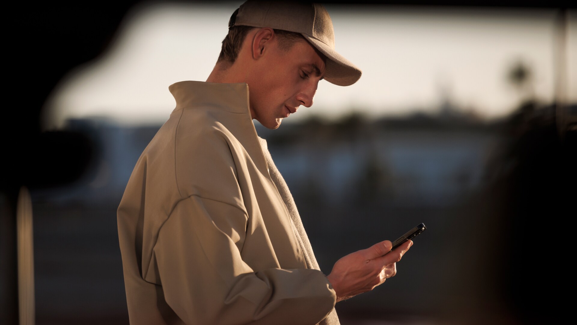 Een man kijkt op zijn smartphone bij de PEUGEOT E-5008
